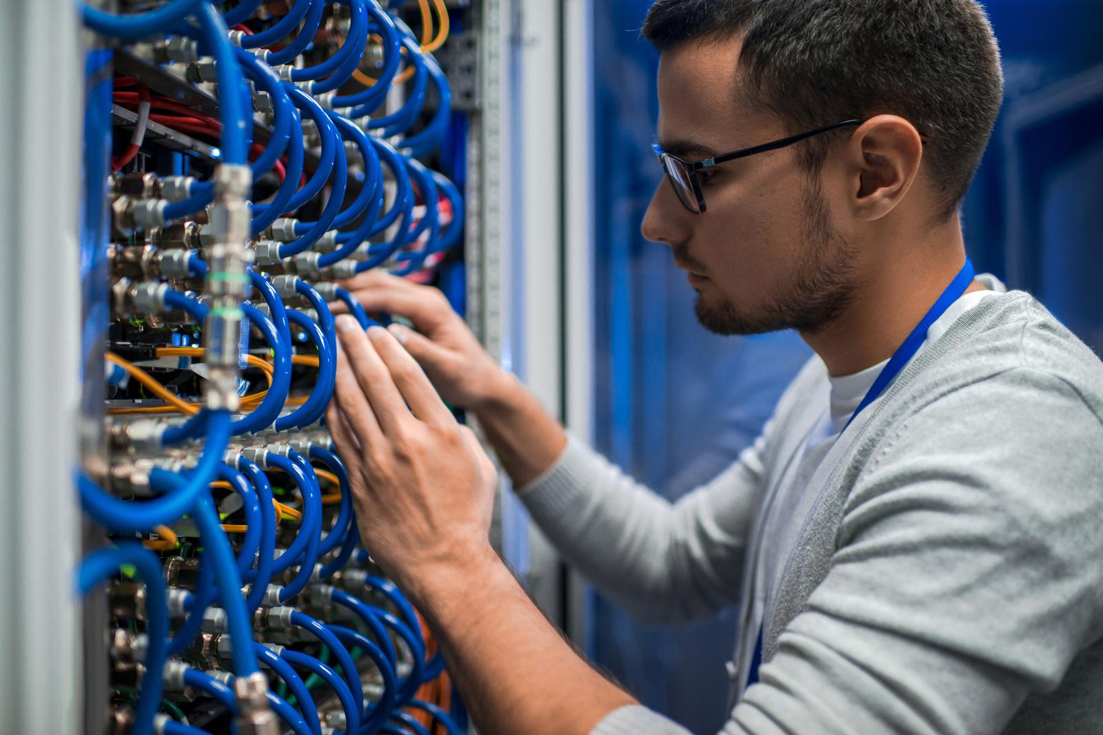 Low-voltage technician connecting network cables at a patch panel