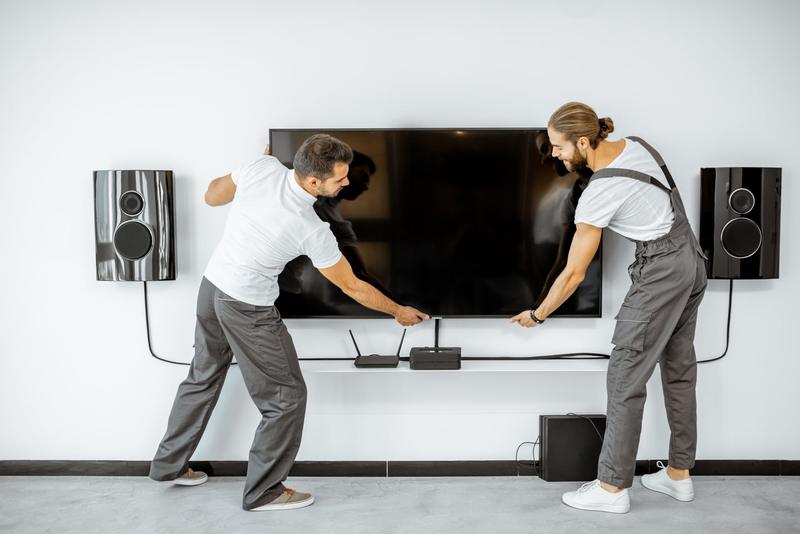 Two installers mounting a flat-screen TV on a living room wall